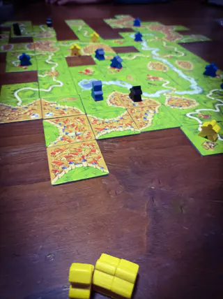 Carcassonne mit ausgelegten Landschaftskarten und Spielfiguren